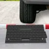 A black rubber car ramp is positioned on a sidewalk in front of a car tire. Náhled obrázku produktu