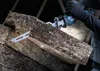 A person is using a reciprocating saw to cut through a piece of insulation material. Voir les images du produit