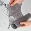 Hands holding a gray silicone mat under running water from a faucet. Podgląd zdjęcia produktu