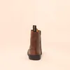 A single brown boot is shown from the back against a light beige background. Voir les images du produit