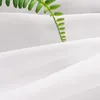 A close-up of a white fabric with a green plant stem resting on it. Produktbild-Vorschau