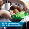 A person is rinsing apples in a pot using a green colander attachment over a sink. Produktbild-Vorschau