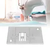 A sewing machine needle plate is shown in the foreground with a blurred sewing machine and a hand in the background. Produktbild-Vorschau