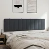 A dark gray upholstered headboard is mounted on a white wall above a bed with white and beige bedding. Produktbild-Vorschau