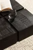 A close-up shot of a dark wooden coffee table with a textured surface, featuring a glass of water and an open book. Anteprima dell’immagine prodotto