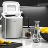 A modern kitchen counter with an ice maker, glasses of ice water, a carafe of water with lemon, and a bowl of lemons. Podgląd zdjęcia produktu