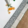 A close-up view of a mirrored surface with crushed diamond inlay, reflecting artificial flowers. Anteprima dell’immagine prodotto