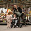 A woman and two young children are at a carousel. Produktbild-Vorschau