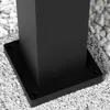 A close-up view of the base of a black metal post, likely part of an outdoor light fixture, resting on a bed of white and gray gravel. Náhľad obrázku produktu