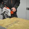 A person is using a circular saw with a laser guide to cut a piece of wood. Produktbild-Vorschau