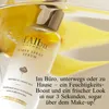 A bottle of d'Alba First Spray Serum is shown with yellow petals or fruit slices in the background, suggesting a refreshing or natural theme. Produktbild-Vorschau