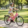 A young girl rides a pink bicycle in a park on a sunny day. Produktbild-Vorschau