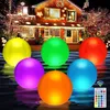 Sechs leuchtende aufblasbare Bälle in Gelb, Grün, Rot, Lila, Orange und Blau, die auf dem Wasser schwimmen, mit einer Fernbedienung, vor einem Haus, das mit Weihnachtslichtern dekoriert ist Anteprima dell’immagine prodotto