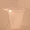 A clear plastic measuring cup with a spout sits on a light-colored surface. Podgląd zdjęcia produktu