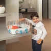 A young boy is interacting with a hamster cage on a shelf. Produktbild-Vorschau