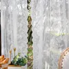 A close-up view of white lace curtains with a natural scene visible through a gap. Produktbild-Vorschau