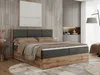 A bedroom scene featuring a large boxspring bed with a wooden frame and upholstered headboard, dressed with bedding. The room has modern, minimalist decor with a large abstract painting on the wall and built-in wardrobes. Produktbild-Vorschau