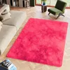 A bright pink rug is placed on a wooden floor in a living room setting, next to a sofa and a green armchair. Produktbild-Vorschau