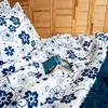 A close-up view of a bed with white and blue floral patterned bedding and a book. Produktbild-Vorschau