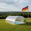 A covered swimming pool in a grassy field with a German flag flying nearby. Produktbild-Vorschau