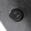 A close-up view of a black circular USB charging port with two USB-A ports and one USB-C port, embedded in a textured gray surface. Anteprima dell’immagine prodotto