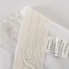 A close-up view of a white fabric product, likely a curtain or textile, showing a care label with washing instructions. Produktbild-Vorschau