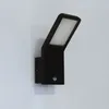 A black LED outdoor wall light with a motion sensor is mounted on a white wall. Produktbild-Vorschau