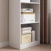 A white bookshelf with various items on its shelves, including boxes and books. Produktbild-Vorschau