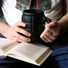 A person holding a grenade-shaped mug over an open book. Voir les images du produit