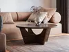 A round coffee table with a vase of dried flowers and two glasses on it, placed in front of a sofa in a living room. Produktbild-Vorschau
