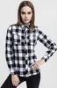 A woman is posing in a studio setting wearing a black and white checkered shirt. Náhled obrázku produktu