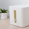 A white cable management box with white cables coming out of it, placed on a wooden surface next to a potted plant. Anteprima dell’immagine prodotto
