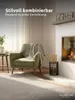 A living room scene with a green armchair, a fireplace, and a fireplace tool set. Produktbild-Vorschau