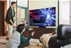 Two people are playing a video game on a large TV in a living room. Produktbild-Vorschau