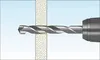 A drill bit is shown drilling through a wall or partition. Náhled obrázku produktu