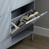 A close-up view of a gray shoe cabinet with a tilted drawer open, showing two pairs of shoes. Náhled obrázku produktu