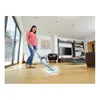 A woman is using a steam mop in a modern living room. Voir les images du produit