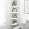 A corner of a room with white corner shelves mounted on the wall, decorated with various items. Voir les images du produit