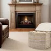 A living room scene with a fireplace, armchair, and a wicker basket. Produktbild-Vorschau
