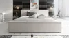 A modern bedroom with a bed, bedside tables, and artwork on the wall.