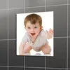 Quadratische Wandkunst mit einem lächelnden Baby mit blauen Augen, das krabbelt, präsentiert an einer grau gefliesten Wand Anteprima dell’immagine prodotto