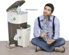 A man is sitting on the floor holding plastic bottles next to a multi-compartment trash can. Náhľad obrázku produktu