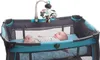 A baby lying in a portable crib with a mobile hanging above. Voir les images du produit