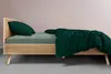 A side view of a bed with green bedding and a wooden frame. Produktbild-Vorschau