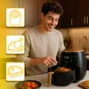 A man is using a black and gold air fryer in a kitchen setting. There are icons representing french fries, a whole chicken, and a steak next to the air fryer. Produktbild-Vorschau
