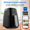 A black air fryer is shown on a wooden surface, with a smartphone displaying recipes in the foreground. The background is a blurred interior scene. Produktbild-Vorschau