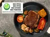 A frying pan with food, including a steak, vegetables, and mushrooms, is shown on a gray surface. A graphic with text is in the upper left corner. Podgląd zdjęcia produktu