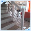 A staircase with a white handrail and silver bars, leading up to a living room area with furniture and a television. Náhled obrázku produktu