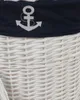 A close-up view of the top portion of a white wicker laundry basket with a navy blue fabric band featuring a white embroidered anchor. Anteprima dell’immagine prodotto