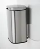 A silver trash can with a lid is mounted on a white wall next to a white object. Náhľad obrázku produktu